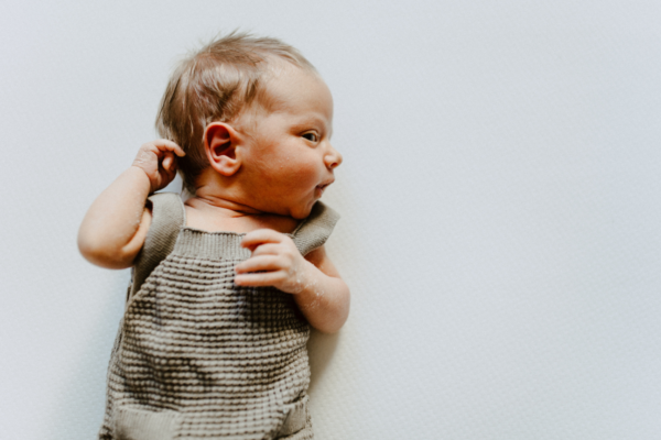 a newborn baby boy in a neutral knit jumper