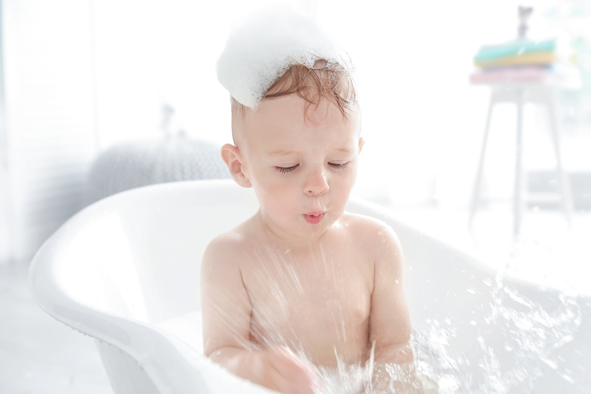 a toddler playing in the bath tub with bubbles