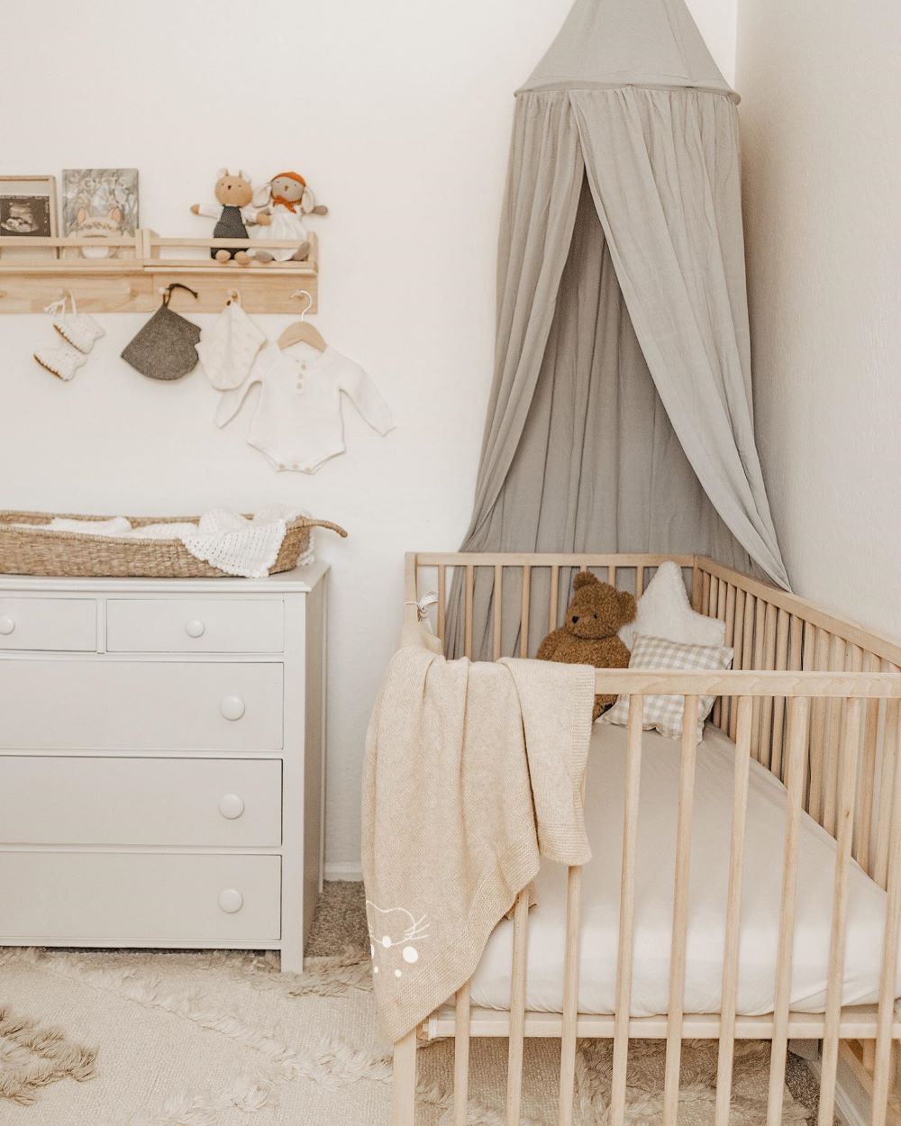 A baby boy nursery with a canopy over the crib and white, beige, and taupe decor and furniture