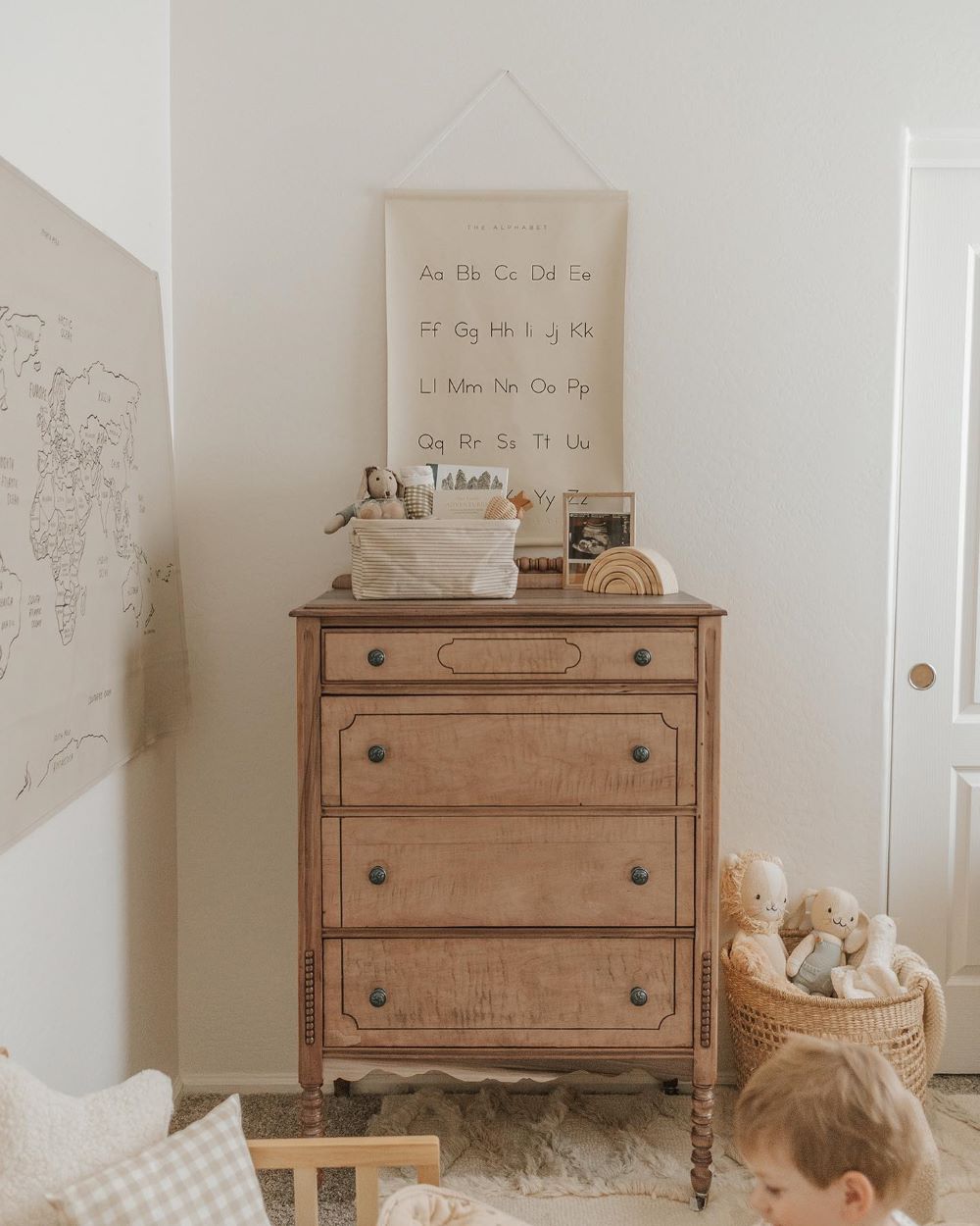 A baby boy nursery featuring cool-toned od furniture, educational wall posters, and vintage style stuffed animals