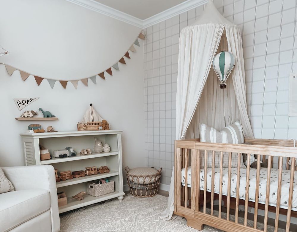 A nursery idea with classic colors and prints and playful and colorful decor like dinosaur figures, hot air balloons, and a crib canopy