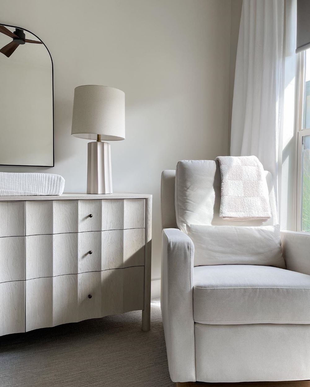 A white nursery room with simple and modern decor and furniture
