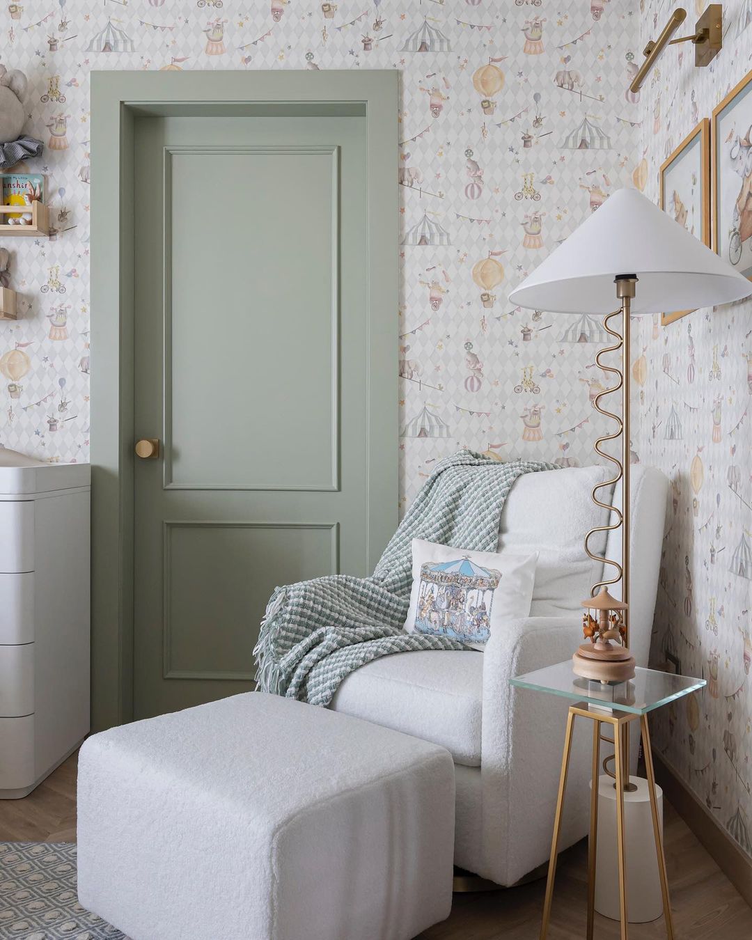 A baby boy nursery room with circus animal wallpaper, a green accent door, and bright white furniture