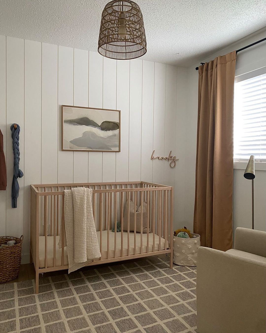 A baby boy nursery room with a shiplap accent wall with beige, brown, and taupe furniture and decor pieces