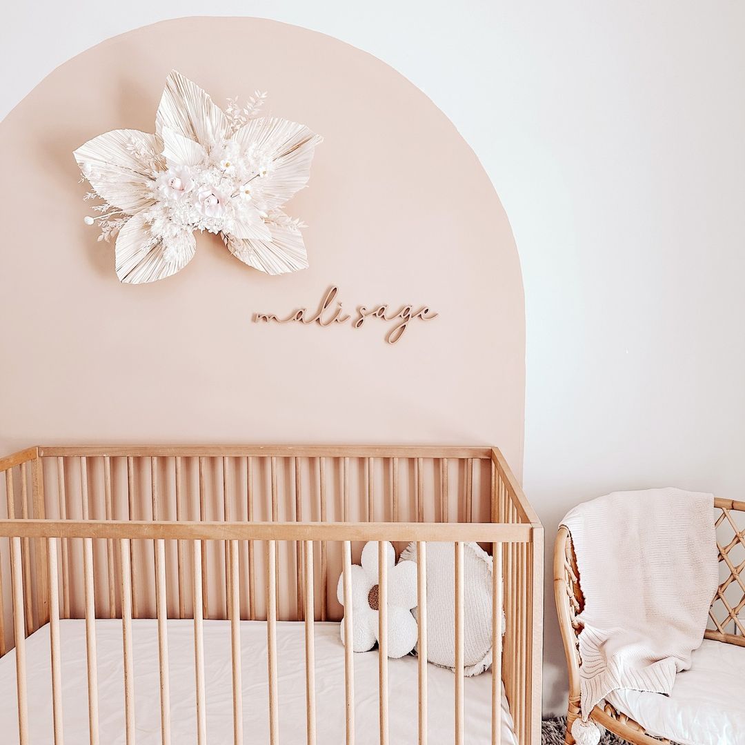 A girls nursery with a pink paint arch, a wooden crate, and flower details