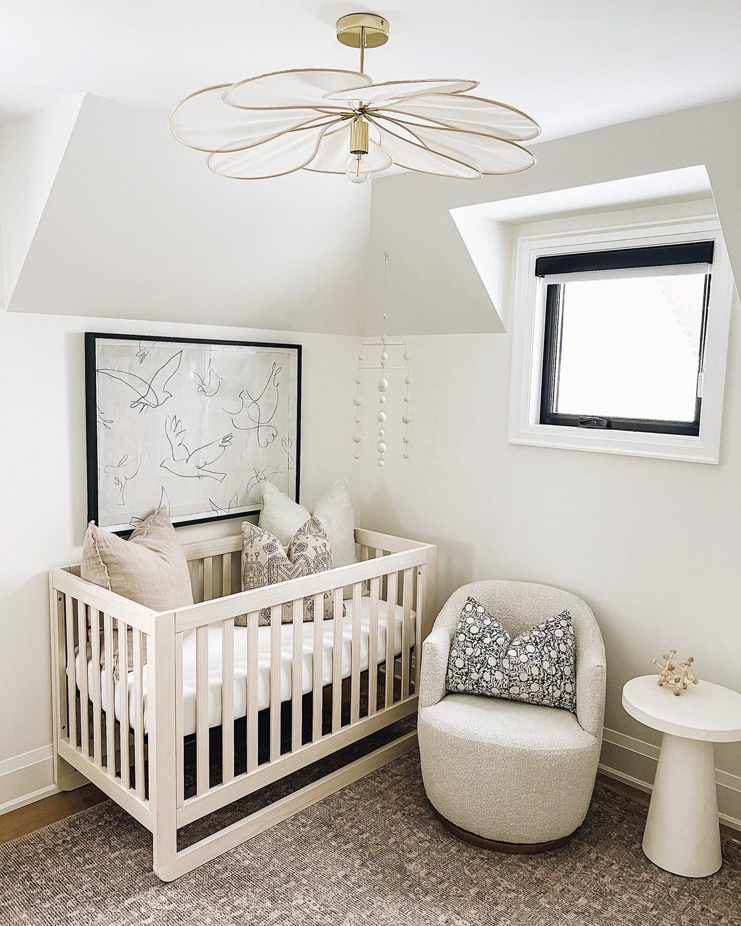 A girls nursery with white walls and decor with pops of black details, minimal animal art, and floral accents