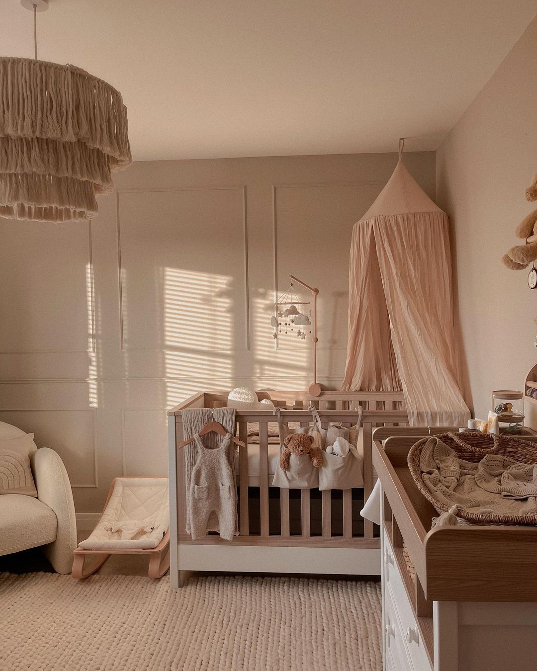 A girl's nursery with a pink princess canopy over the crib, soft tones, and natural soothing elements