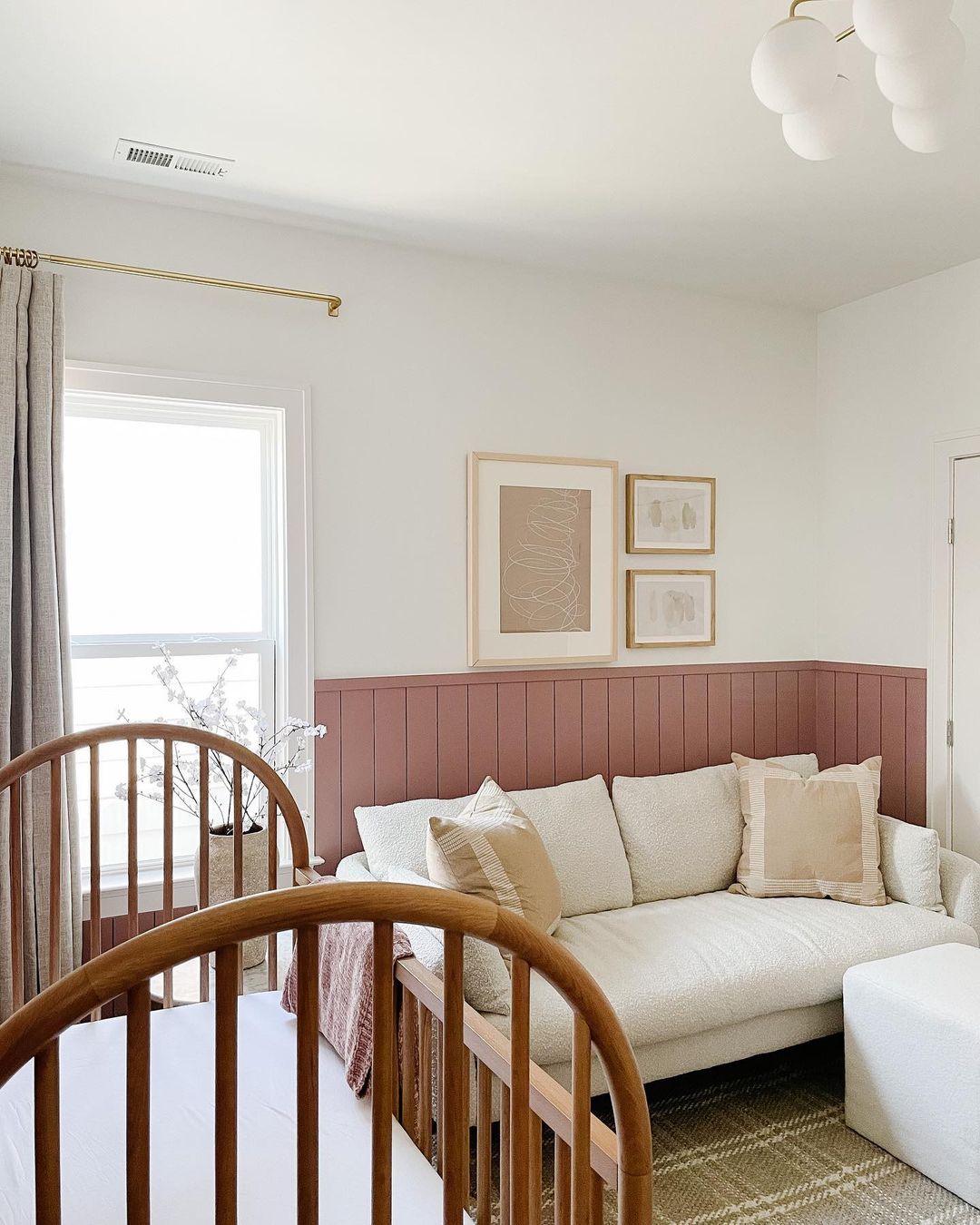 A girls nursery with pink board and batten on white walls with beige and white furniture and decor
