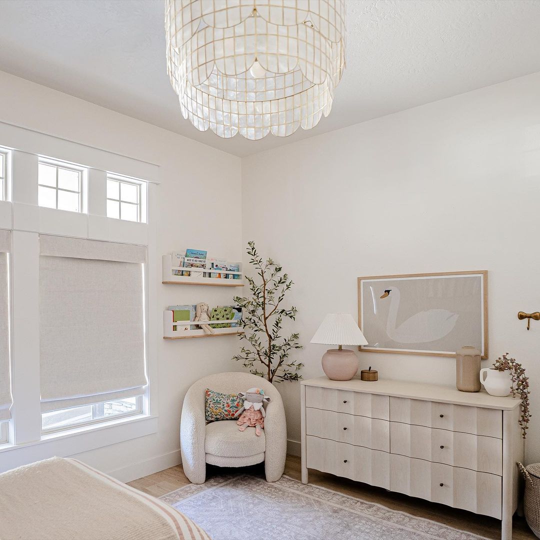 A girls nursery with white walls, furniture, and decor featuring animal and botanical accents