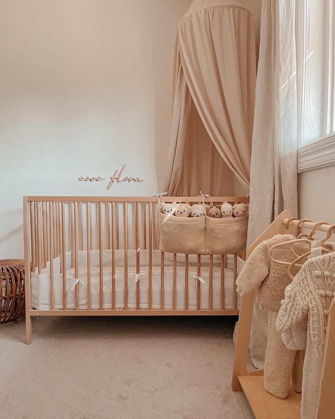 A girls nursery with beige and cream furniture ad decor featuring a princess canopy, stuffed animals, and plush details
