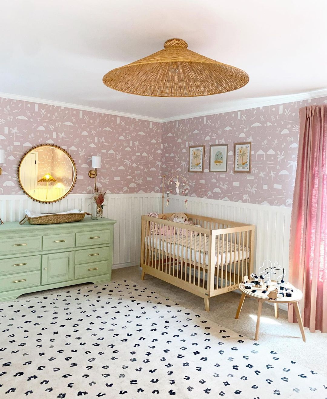A girls nursery with white board and batten, pink tropical wallpaper, pops of color including bright pink and green, and natural wood and raffia elements