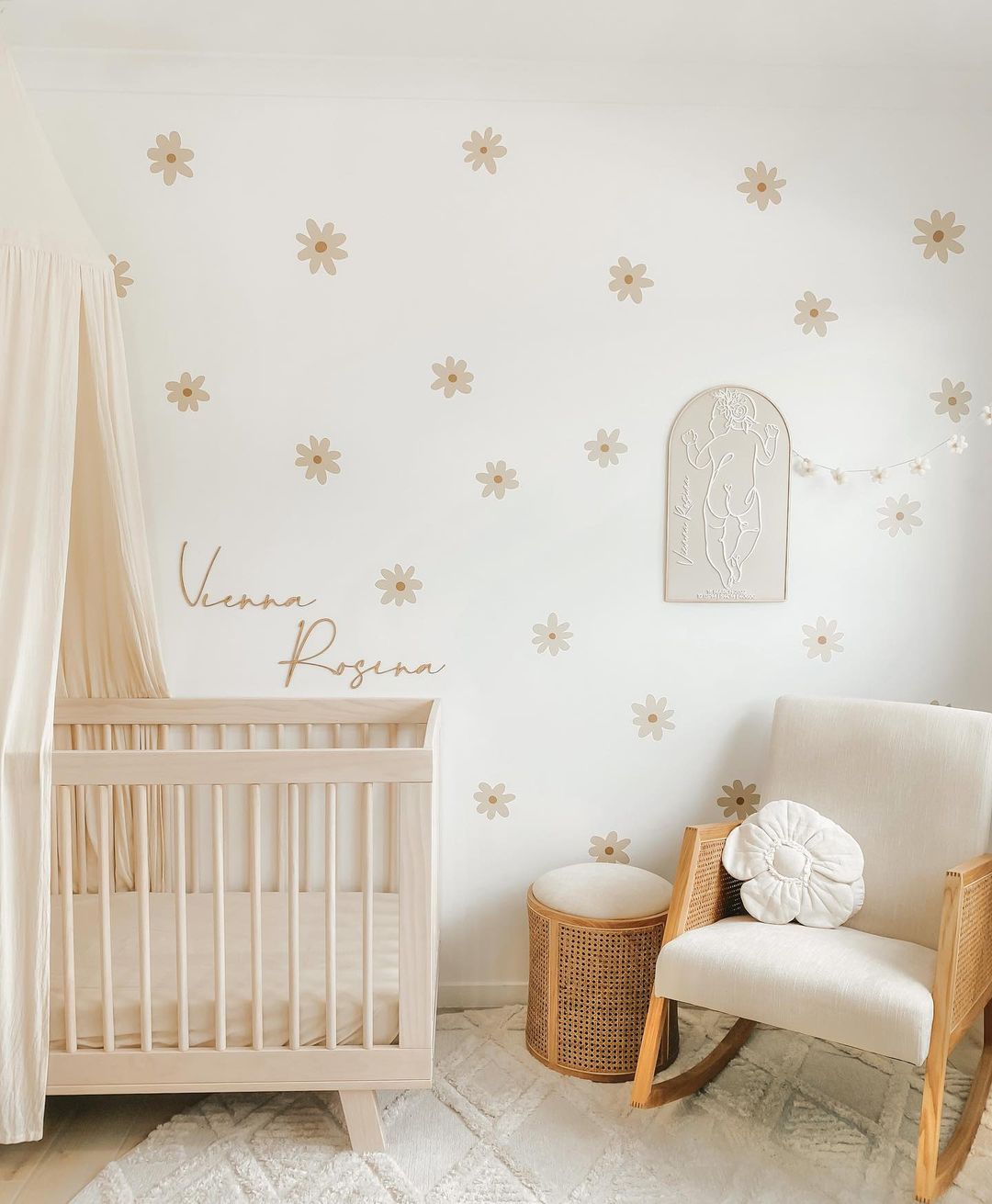 A girls nursery with white and beige floral wallpaper, plus white and beige furniture and decor
