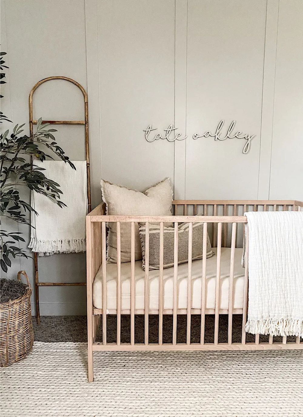 A nursery with soft grey walls, a light wood crib, and classic decor pieces