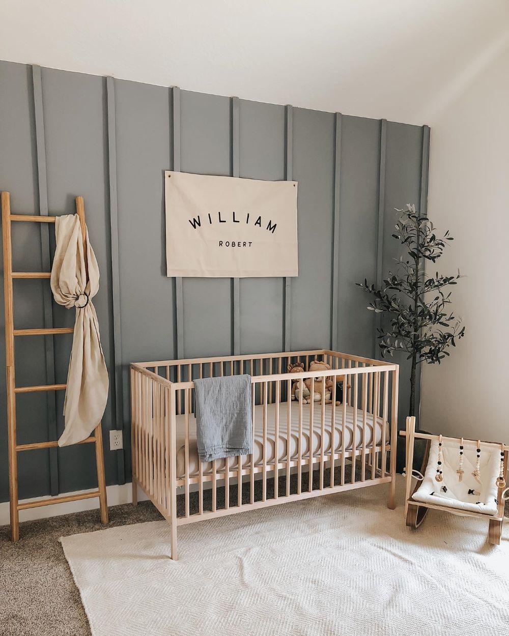 A nursery with soft blue walls, a light wood dresser, and classic decor pieces