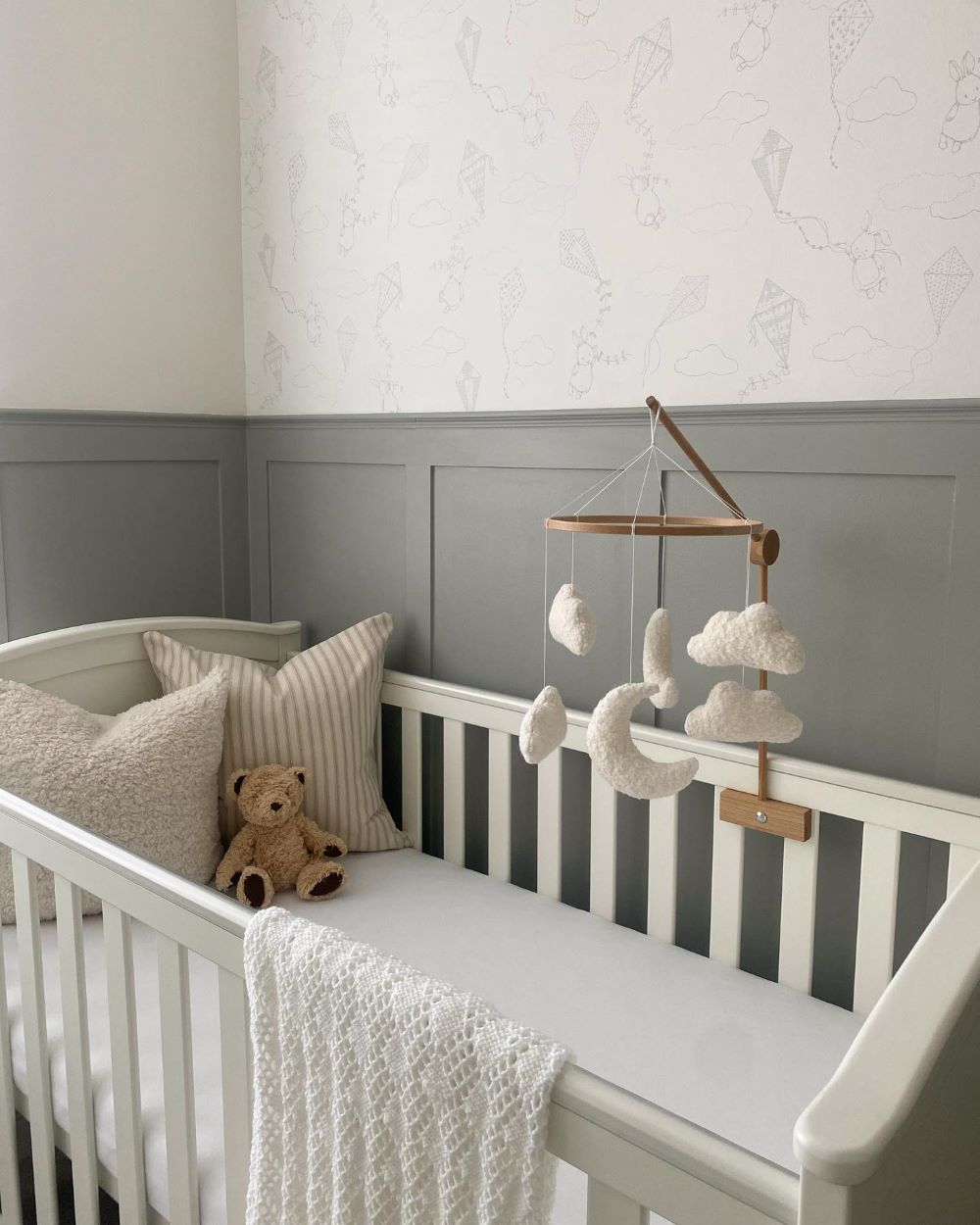 A nursery with rich grey walls, a white crib, and classic decor pieces