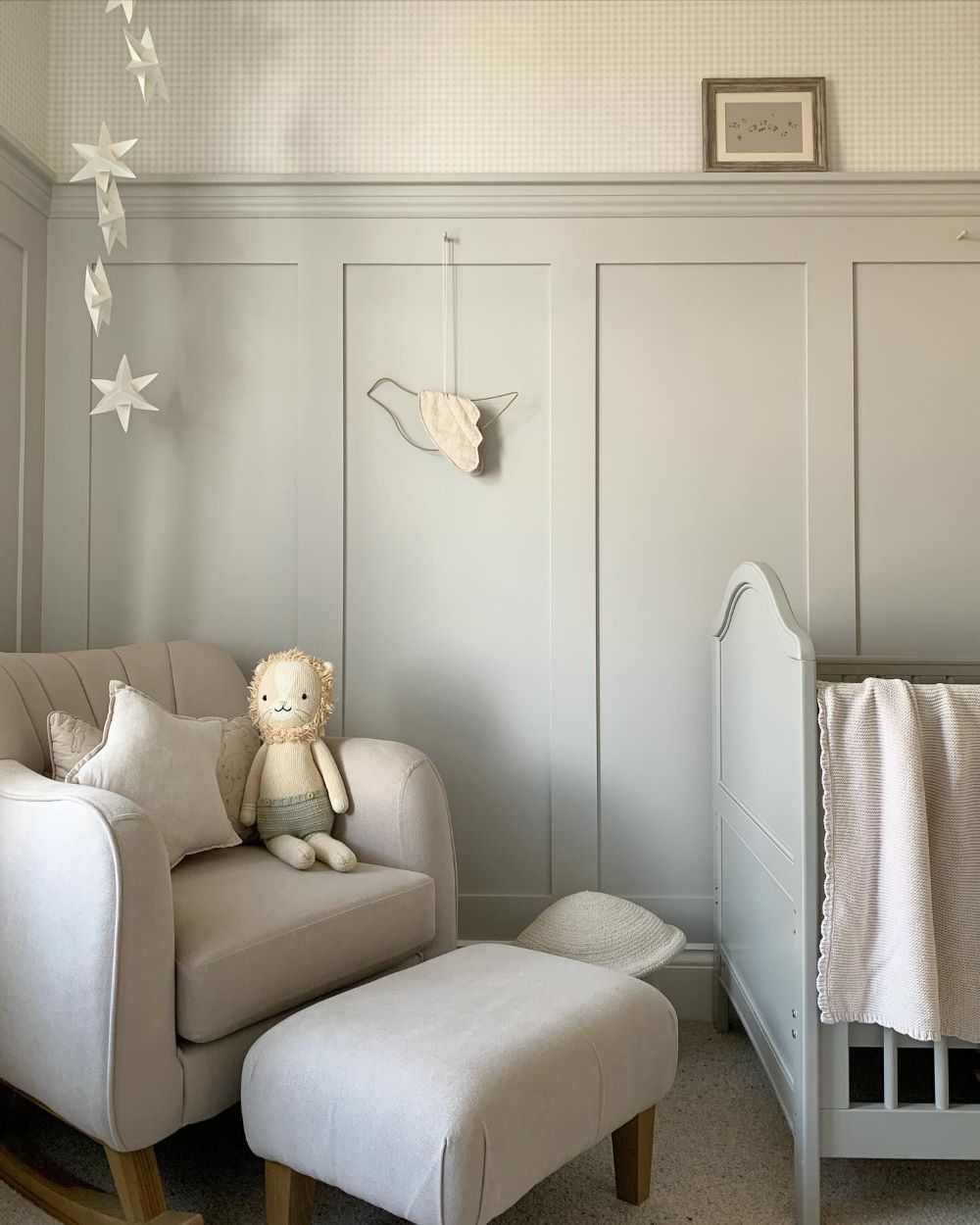 A nursery with soft green walls, a green crib, and classic decor pieces