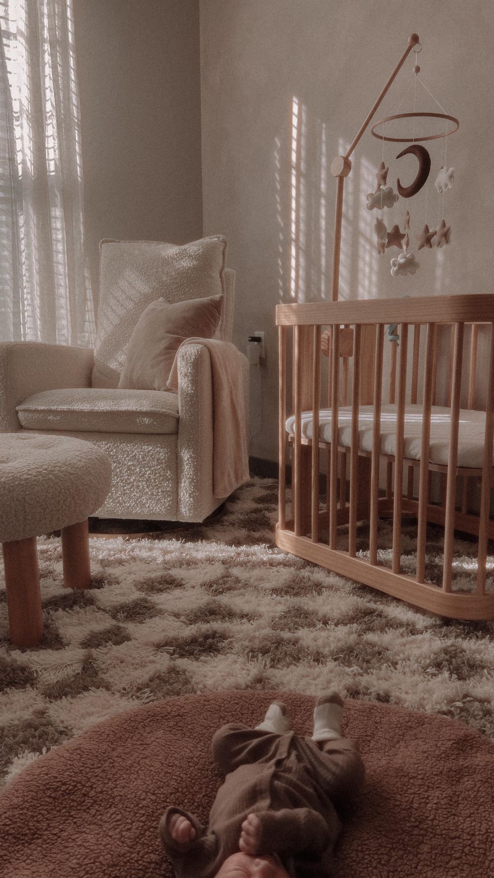 A nursery with soft grey walls, a light wood crib, and playful decor pieces