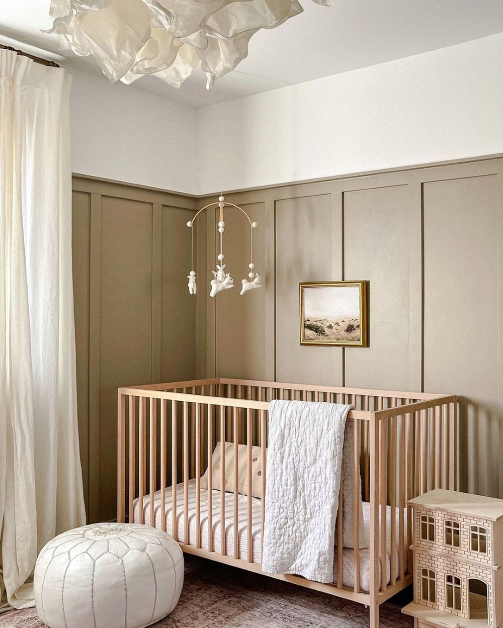 A nursery with green walls, a light wood crib, and classic decor pieces