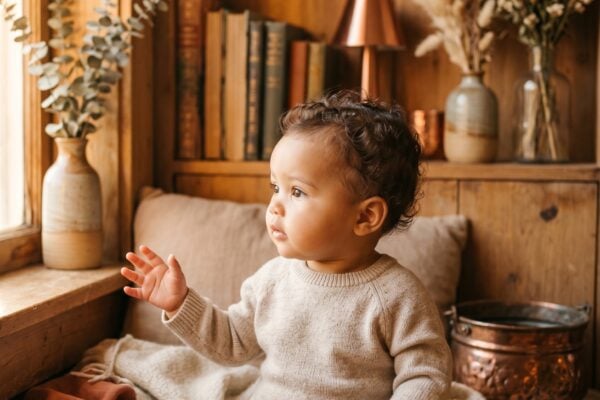 Baby Girl in a cozy reading nook with warm wood and golden light — 200+ Baby Names That Mean Fire — Fierce, Passionate, and Unforgettable