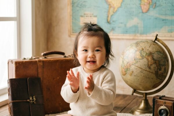 Baby Girl in a bright studio with vintage world maps and weathered globes — 300+ City Names for Babies With a World-Traveler Soul