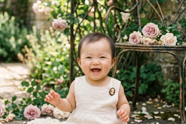 Baby in a sunlit garden with vintage wrought-iron elements and roses — The Edwardian Name Revival of 2026