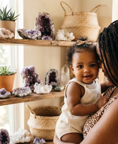 Baby Girl in a sunlit room with geodes and crystals on wooden shelves — 250+ Gemstone and Crystal Baby Names for Your Precious Little One