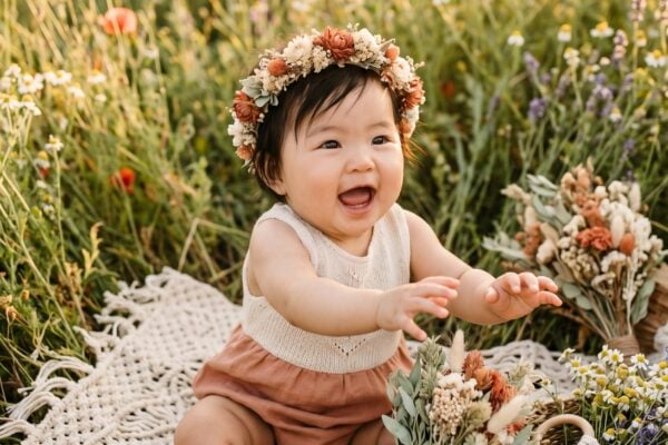 Baby Girl in a wildflower meadow bathed in warm golden hour light — 200+ Hippie Baby Names With Peace, Love, and Flower Power