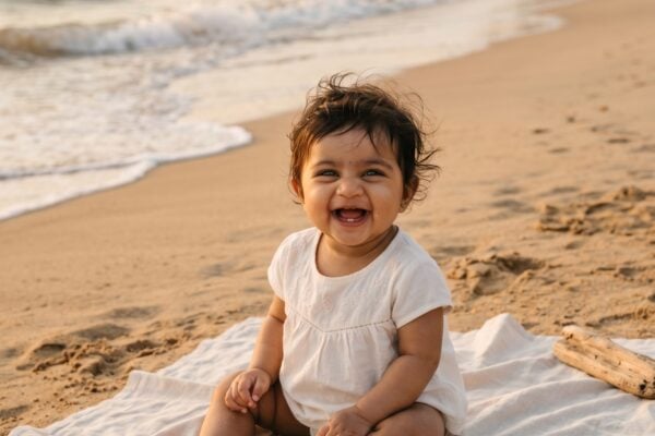 Baby Girl in a soft sandy beach at golden hour near gentle waves — 200+ Island Baby Names for Families Who Love the Sea