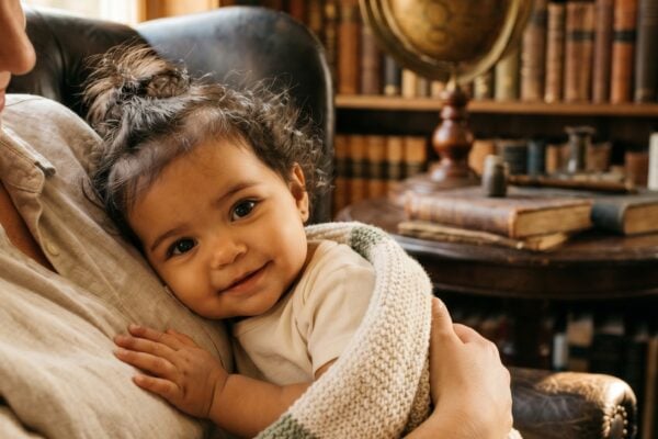 Baby Girl in a warm vintage study nook with leather chair and bookshelves — 200+ Light Academia Baby Names for the Cozy Scholar Aesthetic