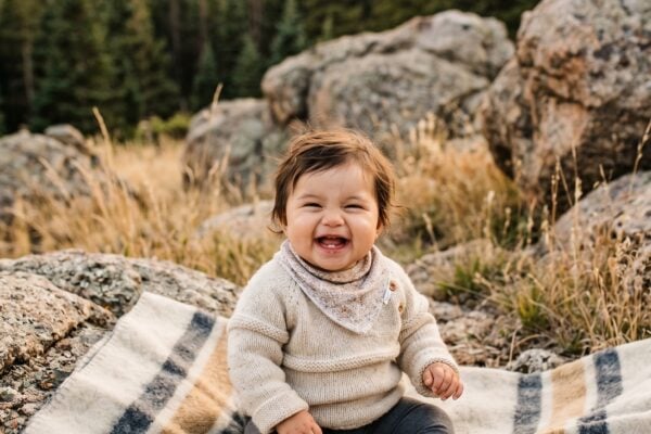 Baby in a rugged mountain foothill with granite boulders and evergreen backdrop — Mountain Baby Names With Granite Strength