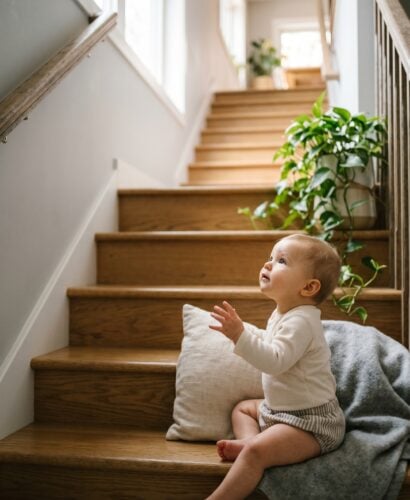 Baby in a sunlit modern staircase ascending to a bright upper level — Rising Baby Names Climbing the Charts