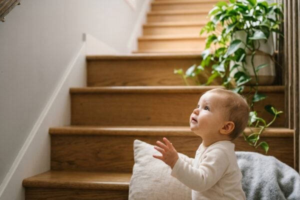 Baby in a sunlit modern staircase ascending to a bright upper level — Rising Baby Names Climbing the Charts