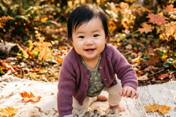 Baby in A sun-dappled forest clearing surrounded by golden autumn foliage — Spellbound Baby Names for Witchy Parents