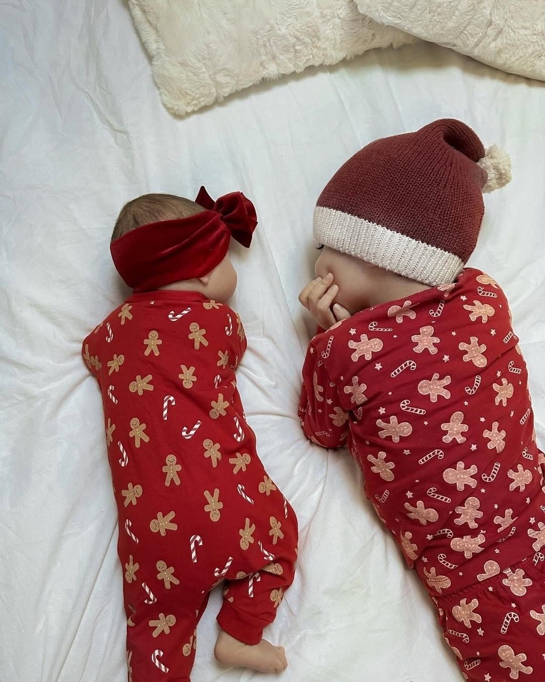 An older sibling and baby wearing coordinating gingerbread-print pajama sets together.