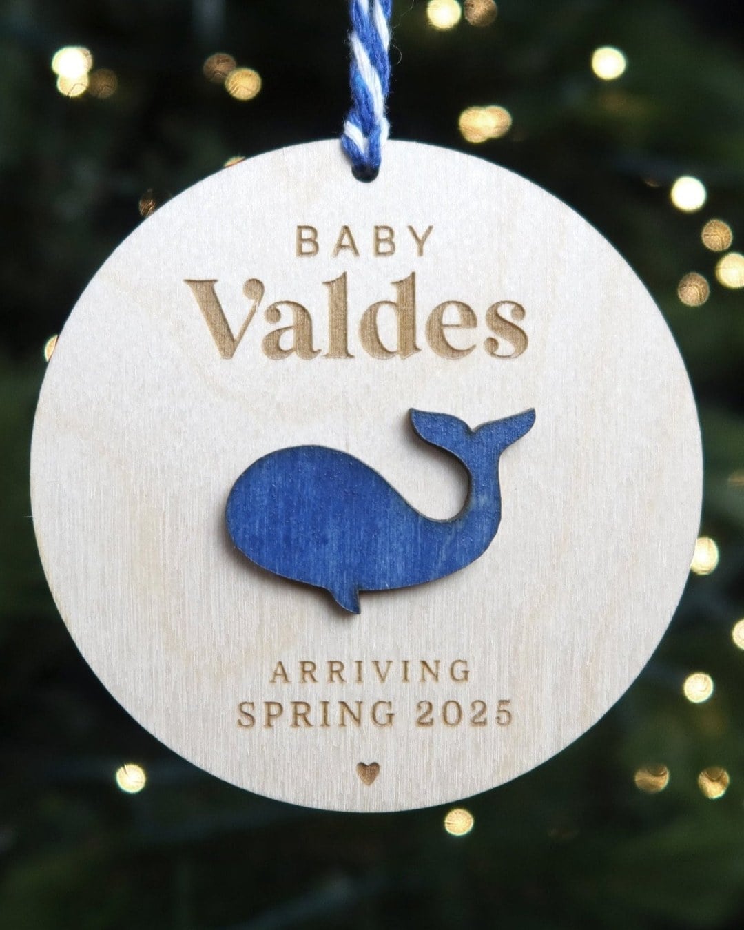 Hand-painted birch wood whale family ornament engraved with last name and due date hanging on the tree