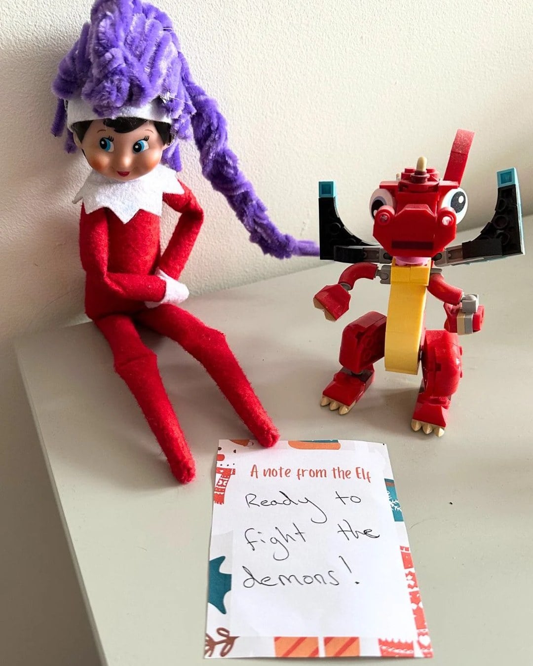 Elf on the Shelf wearing a purple pipe-cleaner braided wig styled like Rumi from KPop Demon Hunters