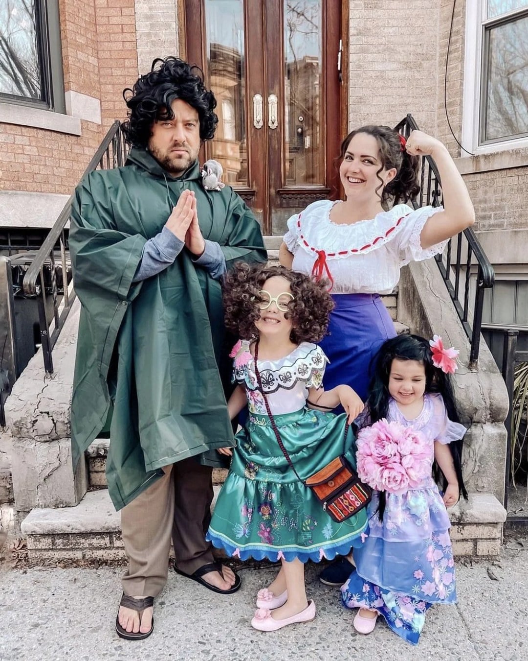 Family dressed as Encanto's Madrigal family members in color-coded outfits representing their magical gifts, including Luisa's strongwoman look and Isabela's flower-covered dress