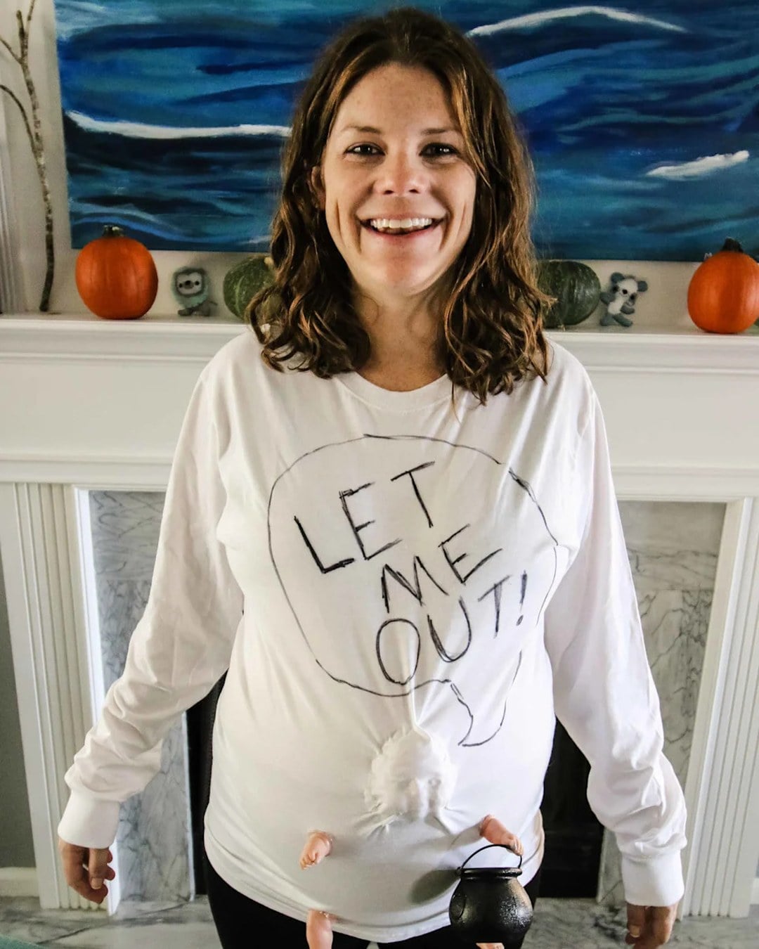 Pregnant belly with a baby doll's face and arms attached to look like a baby escaping