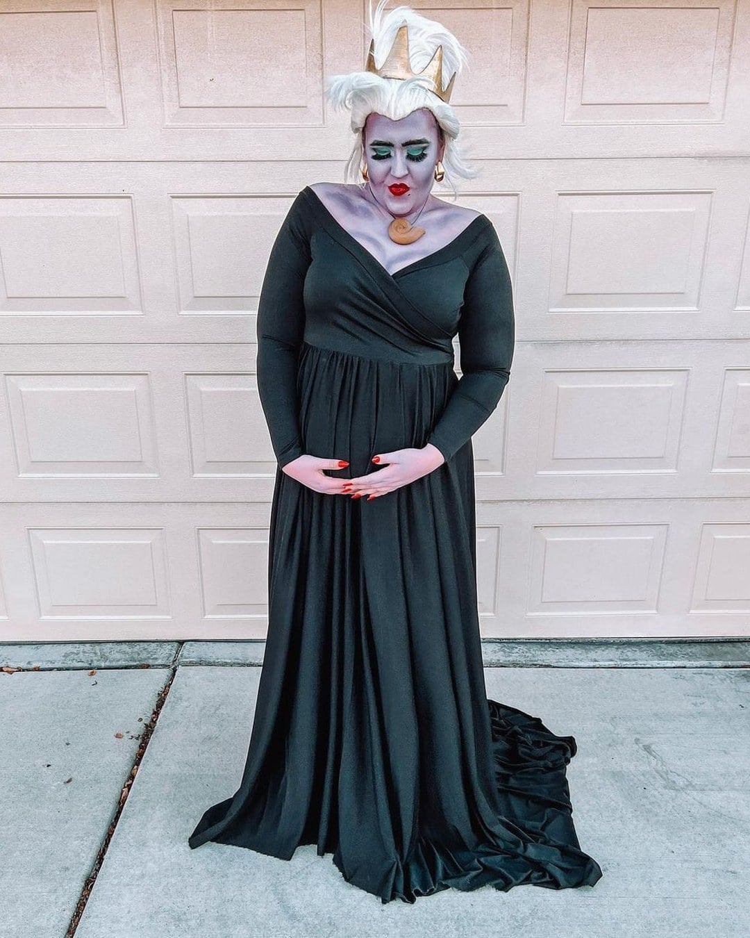 Pregnant woman dressed as Ursula the sea witch with a black dress and purple body paint