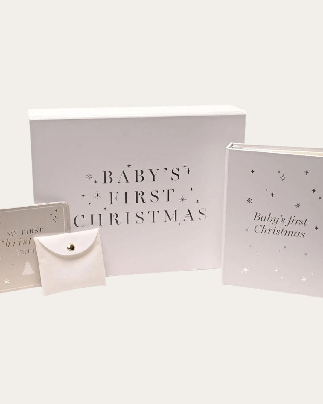 A white Baby's First Christmas keepsake box with a photo album, a tree card and a fabric envelope pouch