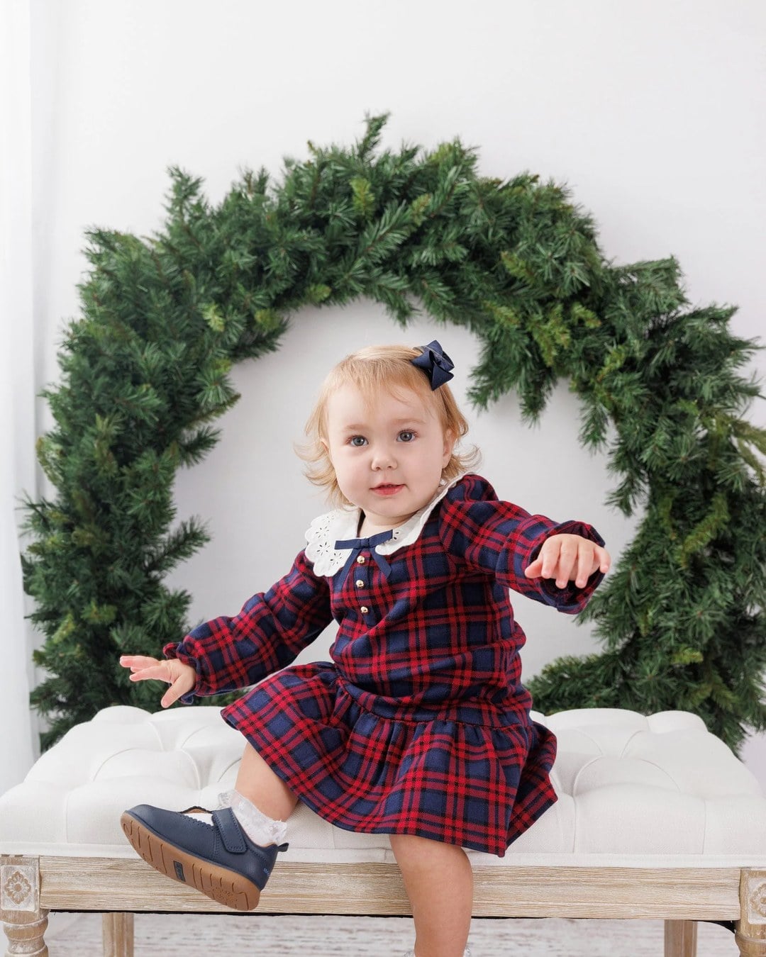 Children posed in front of a wreath backdrop for a holiday portrait