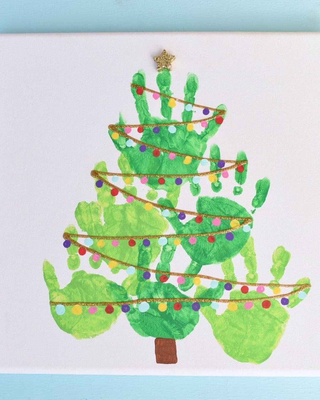 A canvas with overlapping green handprints forming a Christmas tree