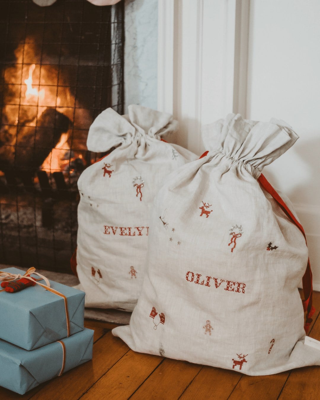 A natural linen Santa sack with a holiday pattern and an embroidered name