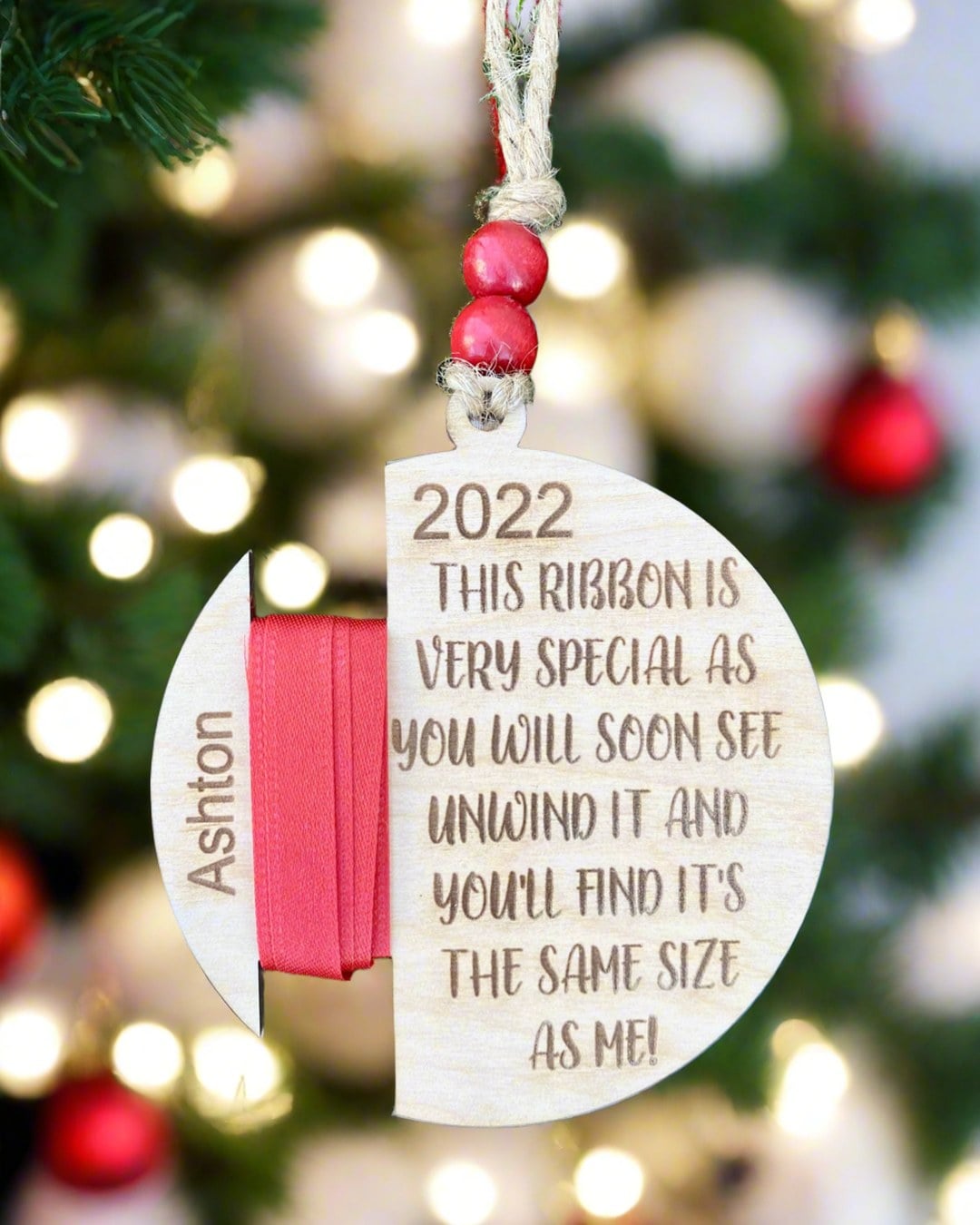 A laser-engraved wooden ornament with a ribbon wrapped around it to mark height