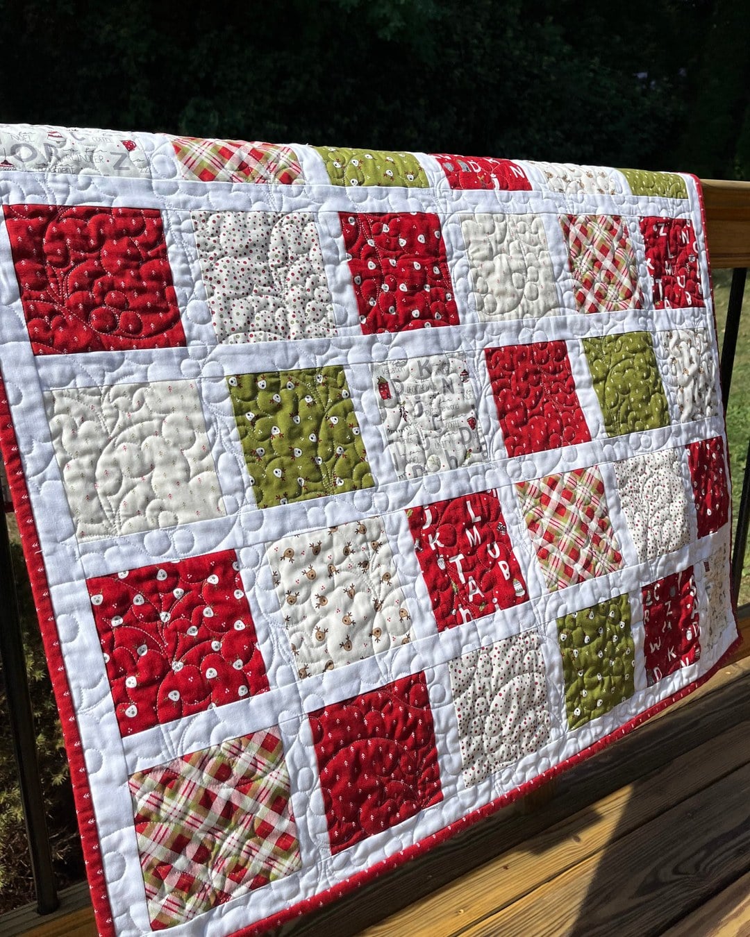 A patchwork Christmas quilt with reindeer heads, pine trees, plaid and alphabet blocks