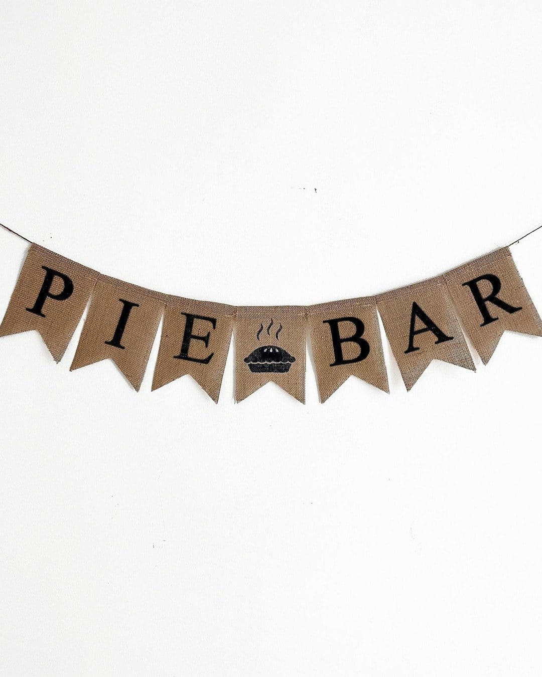 Burlap bunting banner spelling PIE BAR with a small pie icon, hanging on a white wall